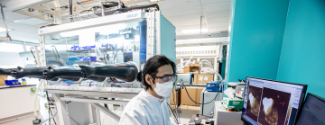 battery researcher examines samples on computer monitor